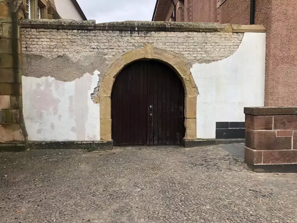 Ein historischer Torbogen mit einer großen Holztür wird saniert